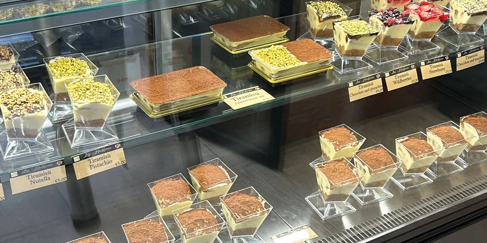 Tiramisu and pastries displayed in a real bakery refrigerated counter